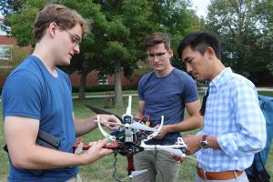 Photo taken in 2019 of (left to right) Neale Van Stralen, Ayberk Yaraneri, and Huy Tran testing a drone on the U of I campus.