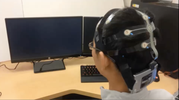 PhD student Yao Li demonstrates the technology that uses brain control interface to send signals to a robot.