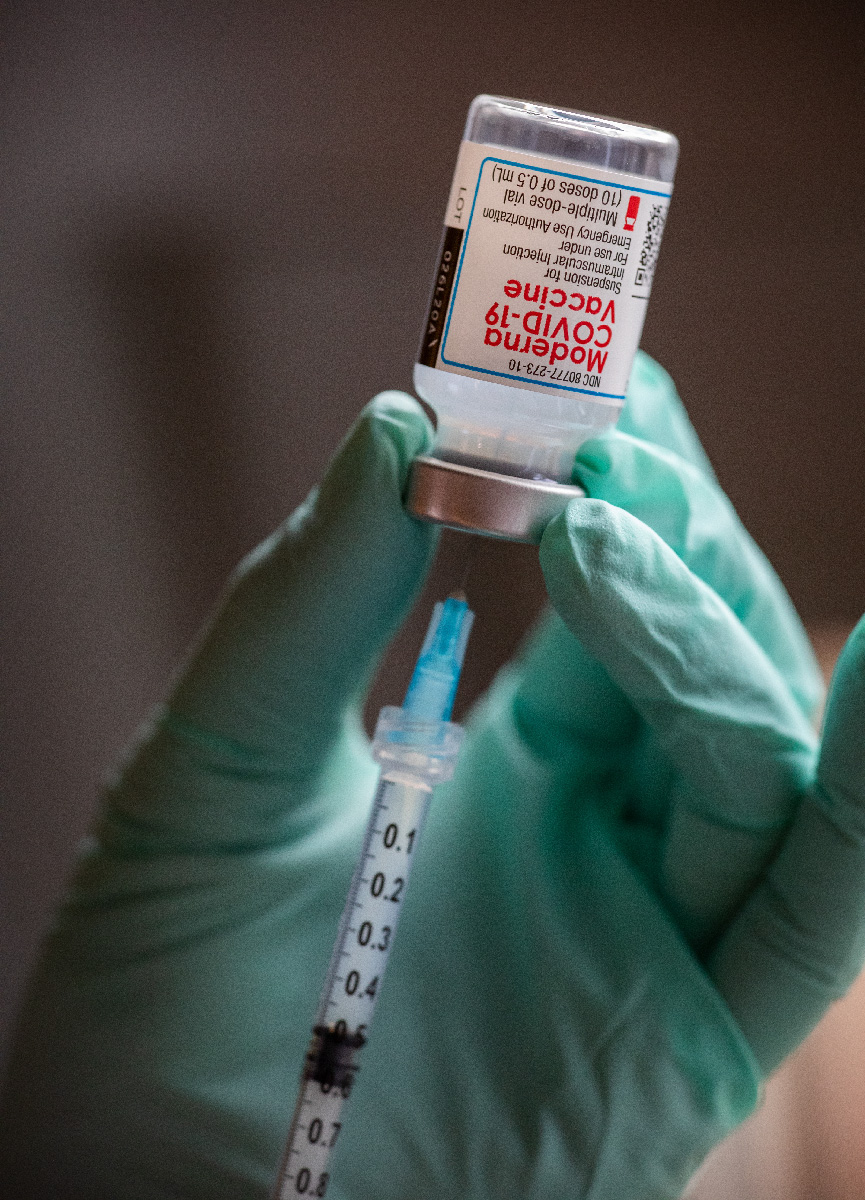 A medical professional draws a vaccine from a vial.